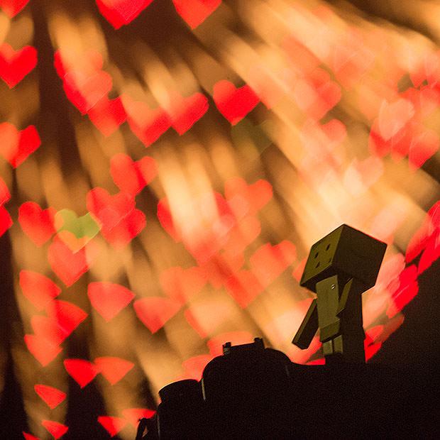 Robot figure standing in front of red heart shaped bokeh