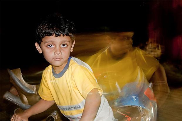 Slow sync flash photo of a boy on a bike at night